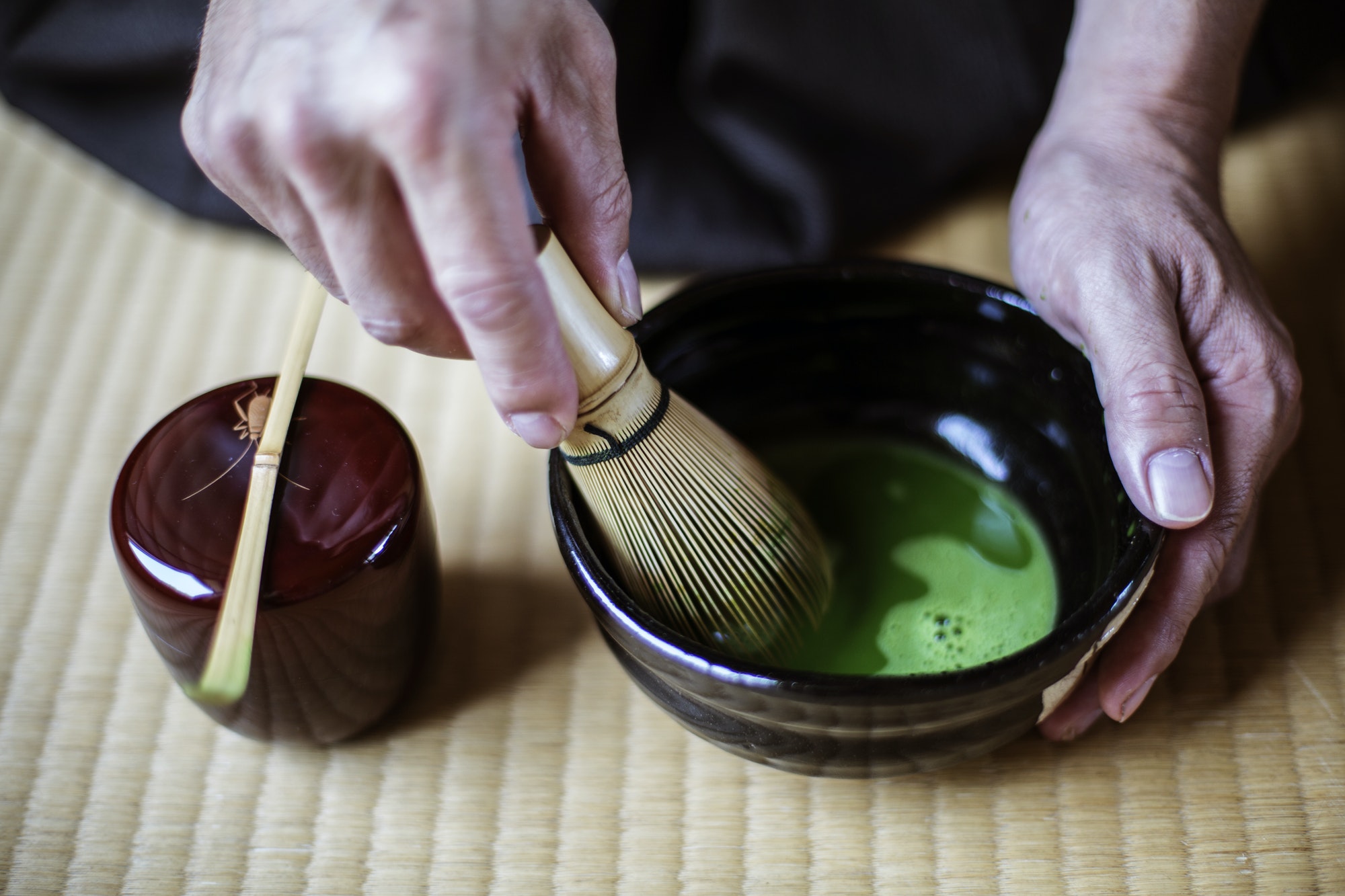 Traditional Japanese Tea Ceremony, man using whisk to prepare green tea.