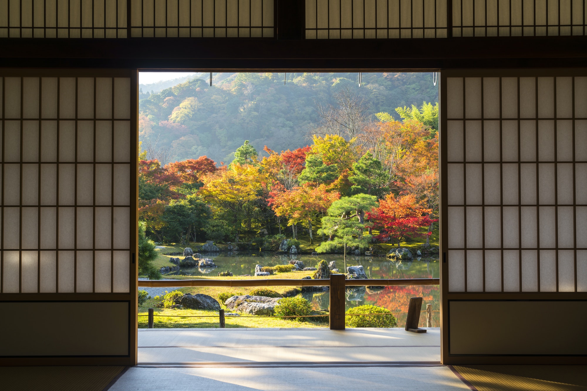 View through traditional Japanese sliding door into an autumn park landscape.