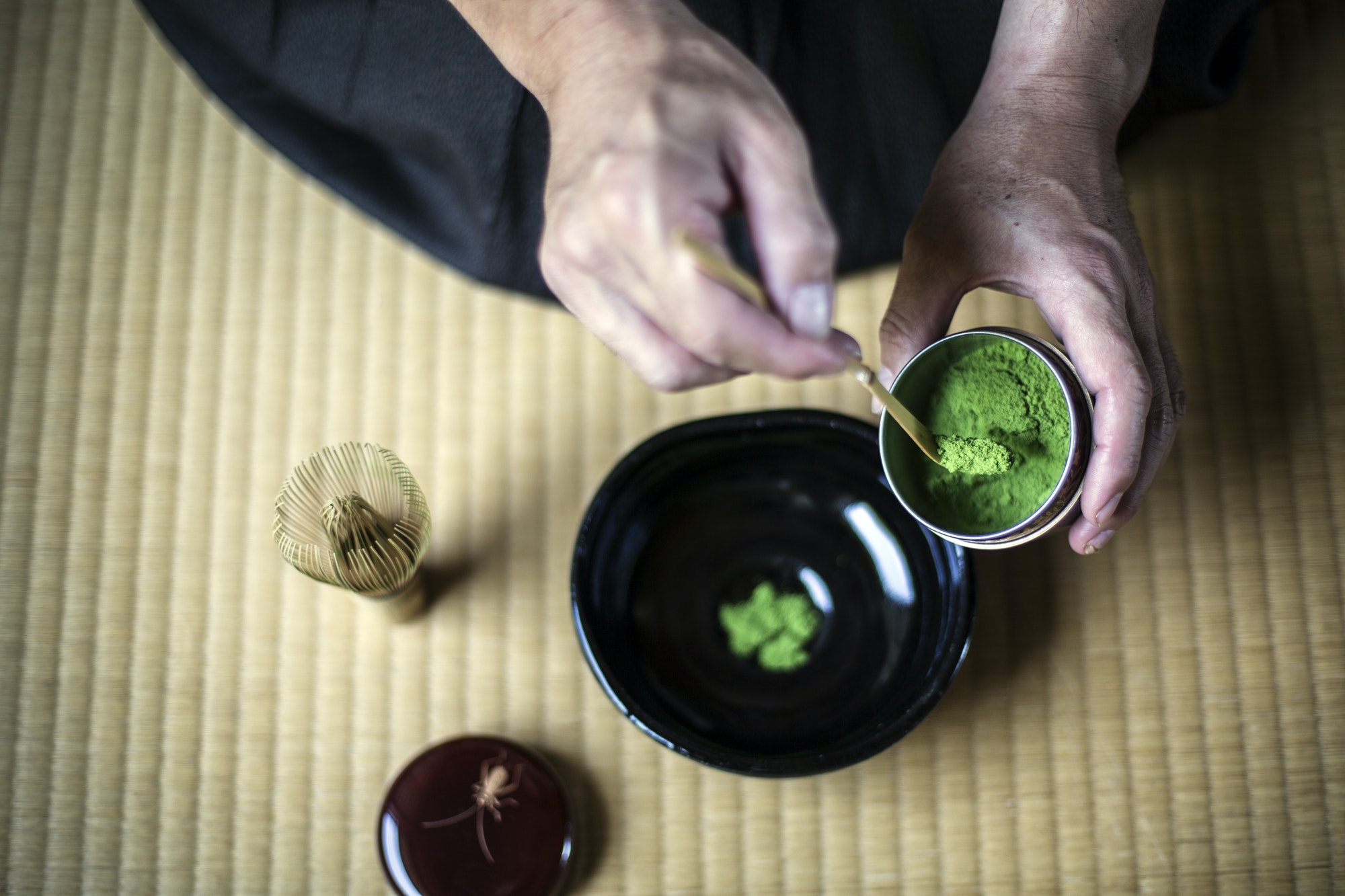 Japanese Tea Ceremony, man spooning green tea powder into bowl.