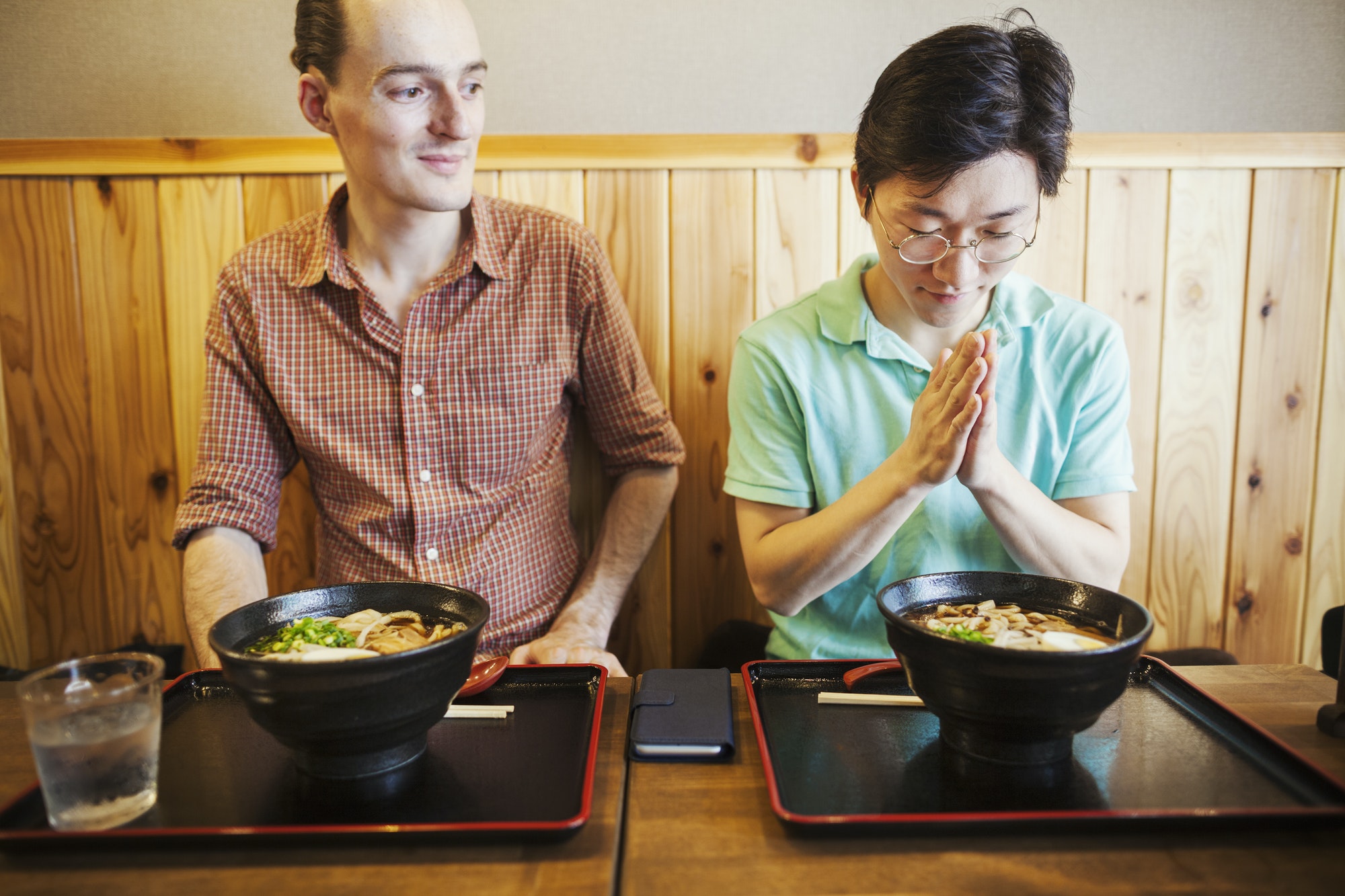 Two people in a Tokyo restaurant, one making a Itadakimasu prayer.