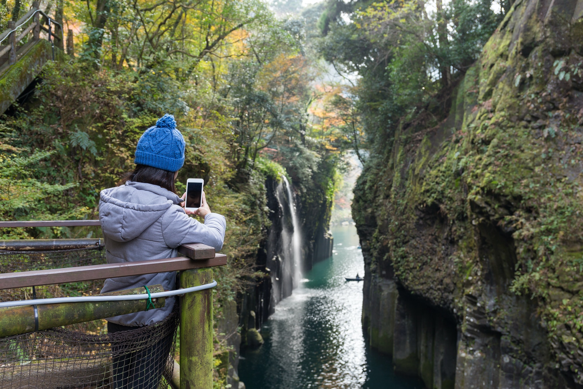 Woman using cellphone to taking photo in Takachiho Gorge